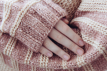 Woman in a beige soft warm knitted sweater folded her hands in the sunlight. Autumn soon