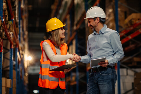 Two people shaking hands in a large warehouse