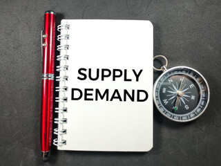 Business concept.Text SUPPLY DEMAND on notebook with pen and compass on black background.