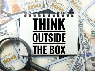 Business concept.Text THINK OUTSIDE THE BOX with magnifying glass and banknote on black background.