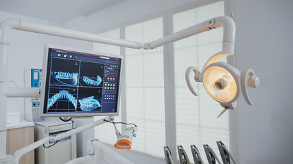Revealing shot of empty stomatology orthodontic office with teeth xray diagnosis images on monitors equipped with dentistry instruments ready for dental surgery. Dentist cabinet for oral care