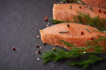 Fresh fish. piece of raw salmon fish fillet, spices on a black stone surface, Delicious fish meat. top view. Healthy food.