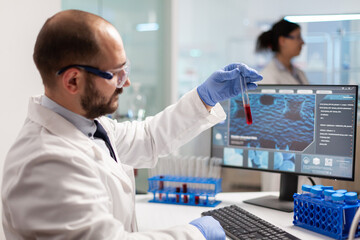 Medical chemist working to find vaccine treatment for virus testing blood sample using micropipette...