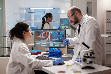 Scientist woring together to find a vaccine in healthcare lab looking at dna sample on computer....