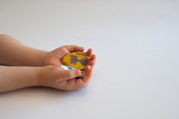 the little girl shows the stones that she has painted in color. selective focus hands. copy space.