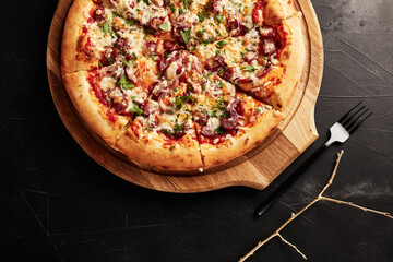 pizza on a wooden base on a black textured background top view