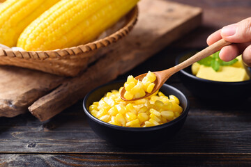 Sweet corn with butter in a bowl eating by spoon on wooden background