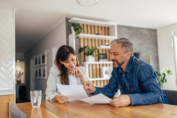Couple at home reading a document and smiling.