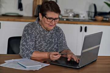 Modern old cheerful lady using online banking, recommending friends by phone