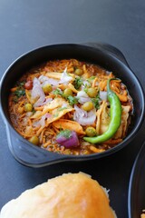 Spicy Misal Pav or usal Pav is a traditional snack or Chaat food from Maharashtra, India. Served with chopped onion, lemon wedges and farsan. Selective focus with copy space