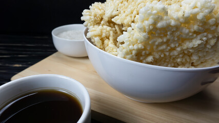Rengginang or Chips made from Traditional Glutinous Rice from Indonesia placed in a white bowl against a black wooden table background.