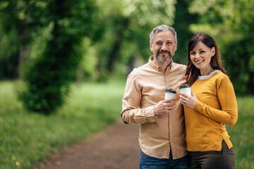 Husband and wife posing for the camera, outside.