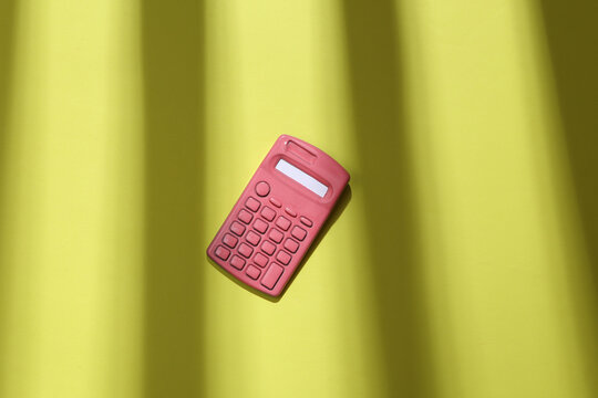 Pink calculator on green background with trendy fashion striped shadow. Minimalism. Abstraction. Concept art