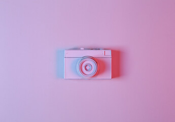 White film camera in pink-blue neon gradient light. Minimalism. Creative layout