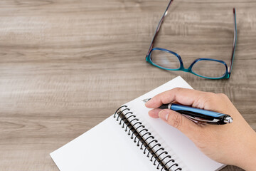 Female hand with notebook on wooden desk. Business, education and people concept.