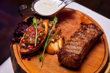 Grilled Veal steak with tomato salsa on a wooden plate. Close-up, selective focus