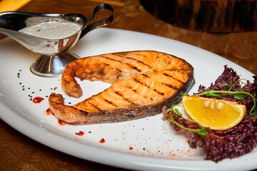 Salmon steak with creamy sauce on a white plate. Close-up, selective focus