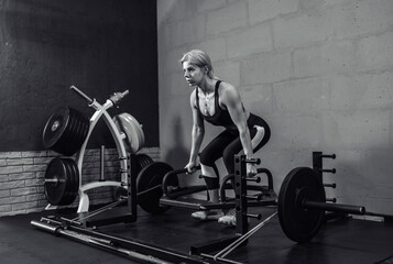 Woman exercising with heavy weights in gym. Fit female doing deadlift workout with barbell