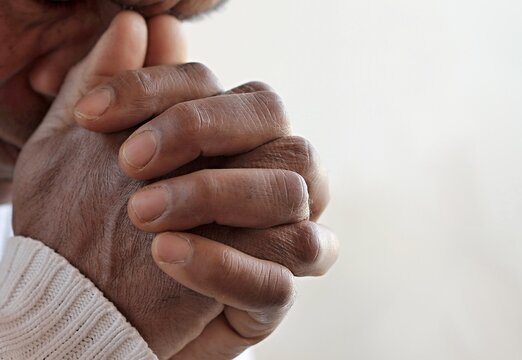 man praying to god with hands together Caribbean man praying with white background stock photo