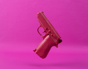 Levitating pink gun on pink background. Minimalistic still life. Creative layout. Concept art