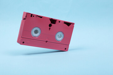 Levitating pink video cassette on blue background. 3D photo. Minimalistic still life. Creative layout. Concept art