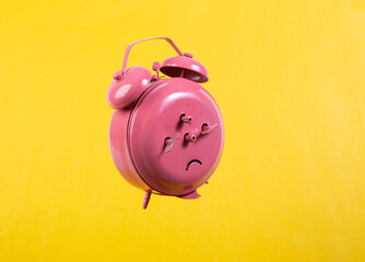 Levitating pink alarm clock on yellow background. Back view. Minimalistic still life. Concept art