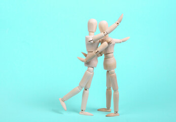 Two hugging wooden puppets on a blue background. Love, romantic concept