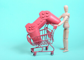 Puppets holding mini shopping trolley with gamepad on blue background. Shopping concept