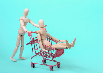Puppets with a mini shopping trolley on a blue background. Shopping concept
