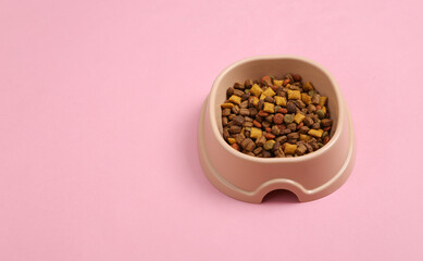 Plastic bowl with cat food on pink background.