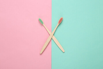 Eco-friendly bamboo toothbrushes on pink blue background. Top view.