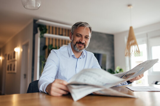 Adult man reading today's newspaper before coffee.