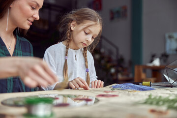 Fototapeta premium Flourist shop with different kinds of dryed flowers. Young happy confident specialist is working with her female kid.