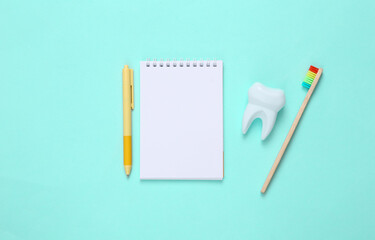 Eco-friendly bamboo toothbrush, notebook and tooth on blue background. Dental care concept..Top view.
