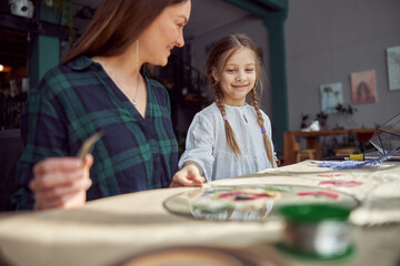 Fototapeta premium Flourist shop with different kinds of dryed flowers. Young happy confident specialist is working with her female kid.