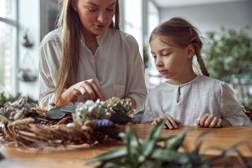 Obraz na płótnie Canvas Flourist shop with different kinds of dryed flowers. Young happy confident specialist is working with her female kid.