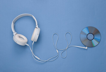Musical layout. Headphones and cd on blue background. Top view. Flat lay - obrazy, fototapety, plakaty