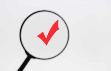 Check mark approved symbol on the monitor screen through magnifying glass