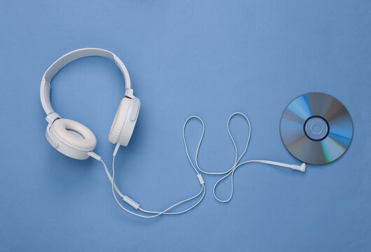 Musical layout. Headphones and cd on blue background. Top view. Flat lay