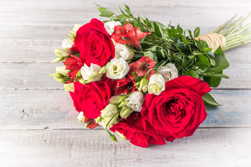 bouquet of red and white roses with alstroemeria on a light rustic wooden table