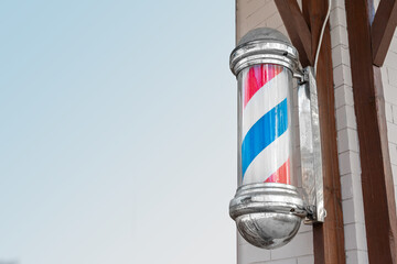 American vintage barber pole sign with a helical stripe (red, white, and blue) on the wall of a...