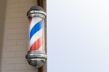 American vintage barber pole sign with a helical stripe (red, white, and blue) on the wall of a...