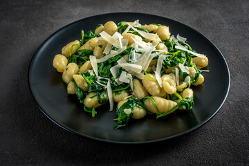 gnocchi with spinach and parmesan on a dark background with copy space