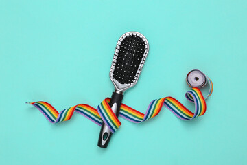 Hair brush with rainbow tape on blue background. Beauty layout.