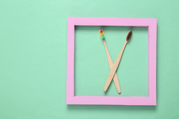 Eco-friendly bamboo toothbrushes with pink frame on blue background. Minimalism layout