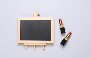 Lipstick with empty chalk board on white background. Beauty concept