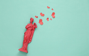 Antique statue with hearts on blue background. Romantic, love scene. Top view