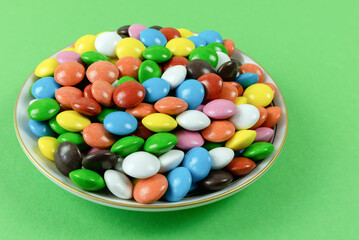 Round milk chocolate balls on a plate on a green background