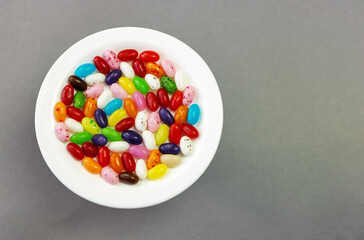 Assorted jelly beans on a plate on a gray background