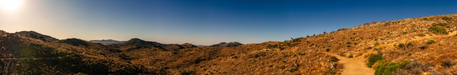 Panorama shot of dry desert hills and dusty path in joshua tree national park in america at sunset
